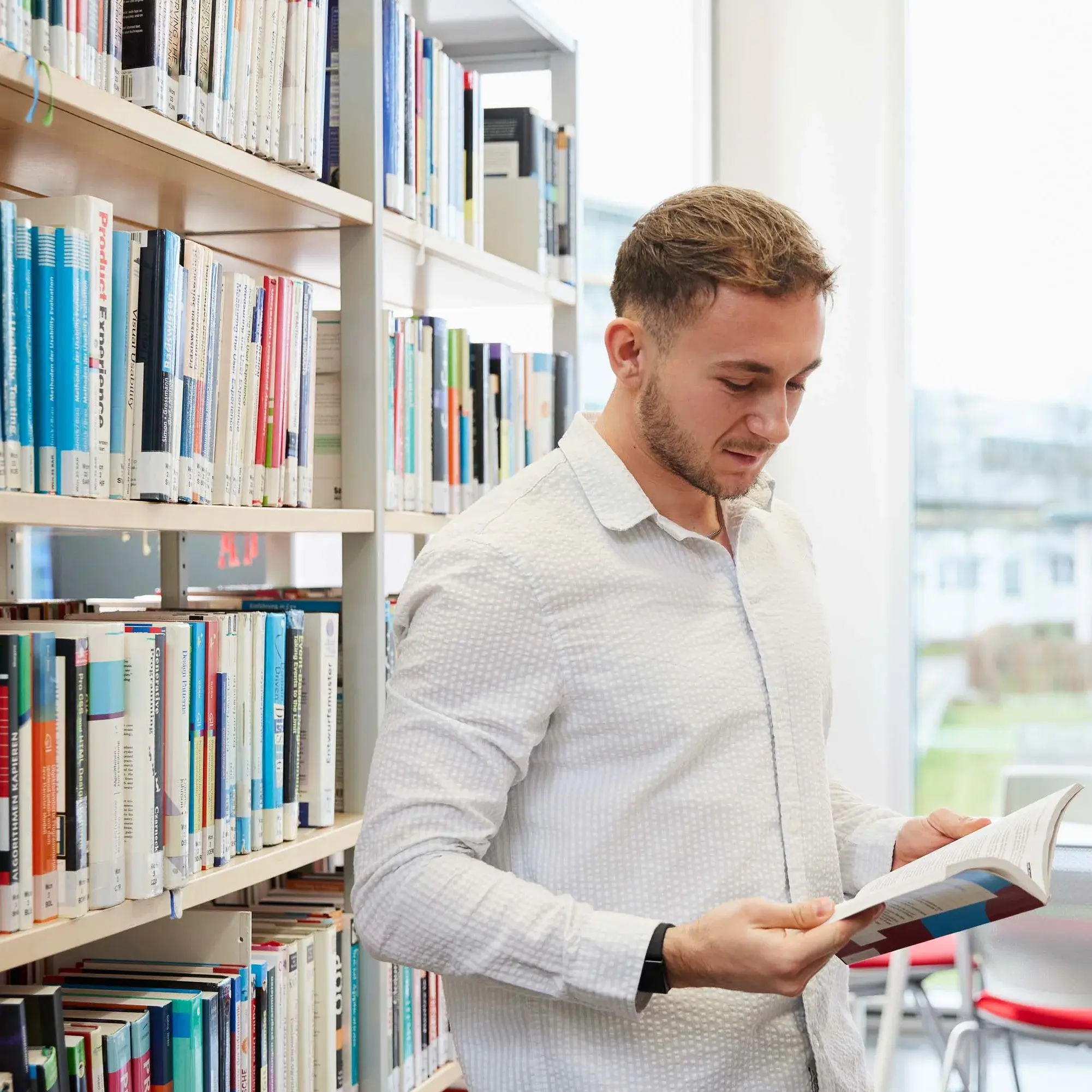 Ein Studierender liest ein Buch in der Bibliothek der Hochschule der Medien.