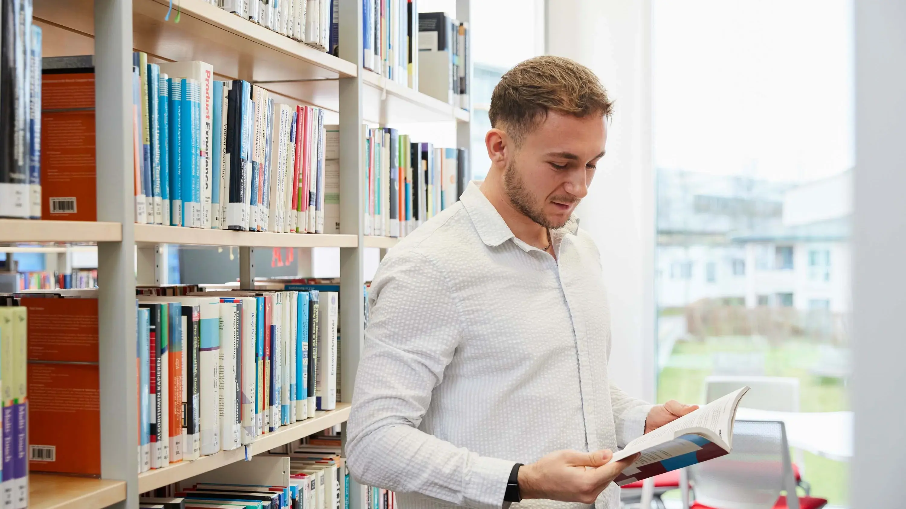 Ein Studierender liest ein Buch in der Bibliothek der Hochschule der Medien.